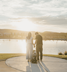 couple and their dog overlooking a pond at desert color