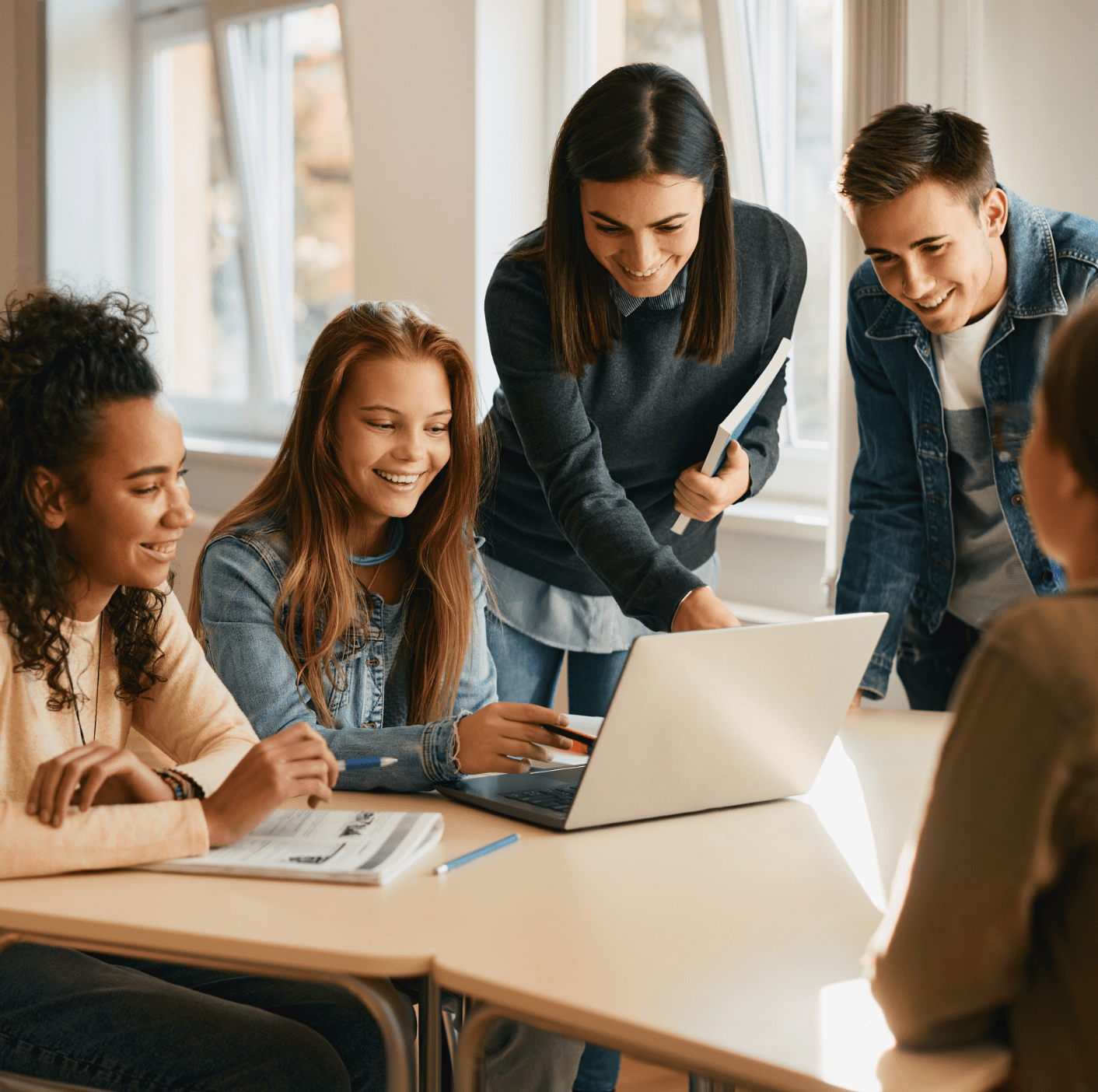 Group of people looking at a laptop on a desk