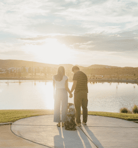couple and their dog overlooking a pond at desert color